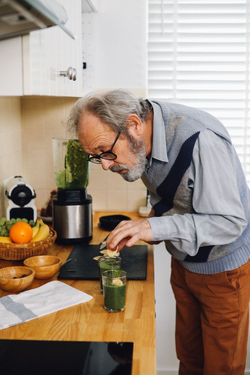 Starší muž připravuje v kuchyni zelené smoothie