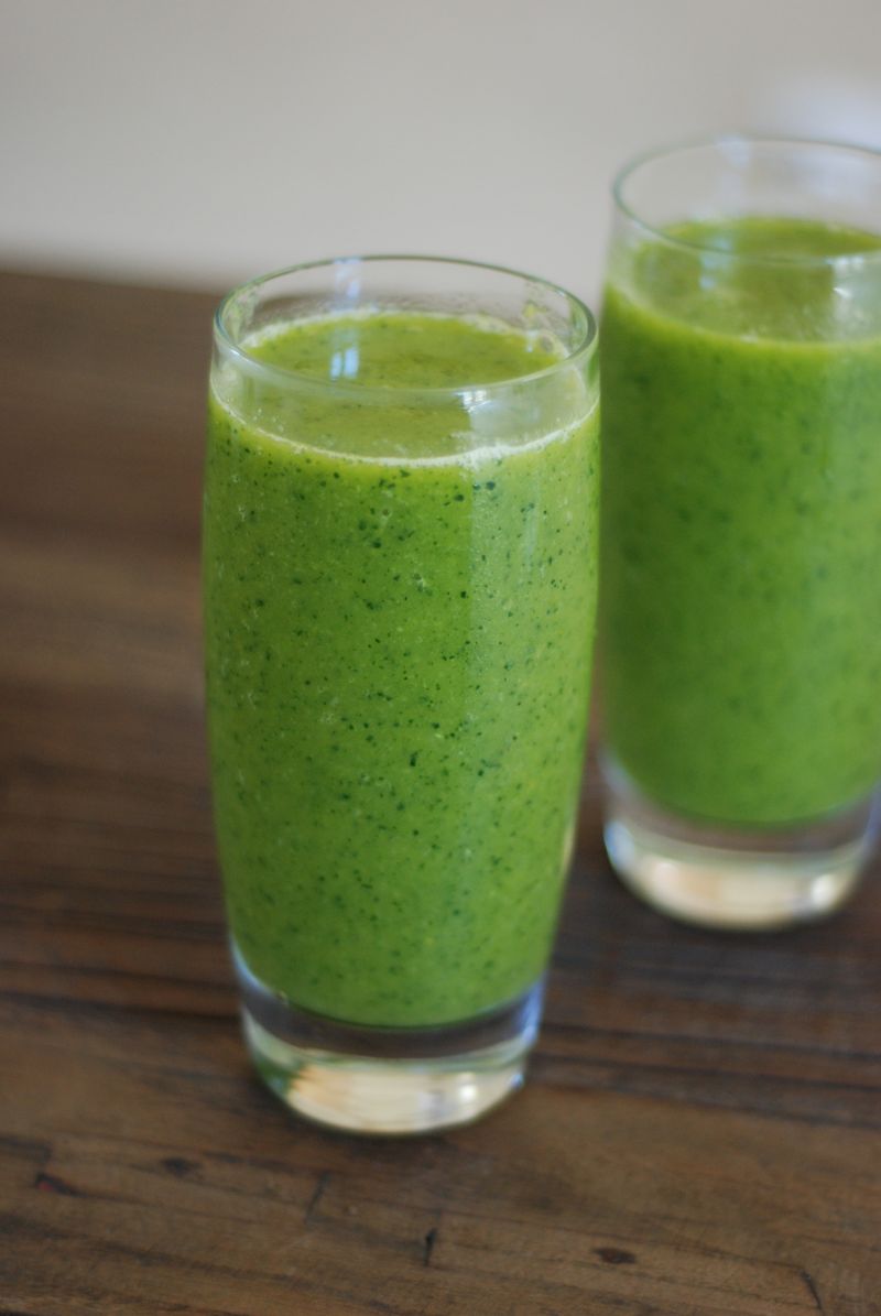 Dvě sklenice zeleného smoothie na dřevěném stole